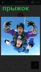 На парашюте мужчина с женщиной совершают прыжок вместе, показывая жестами свое удовольствие