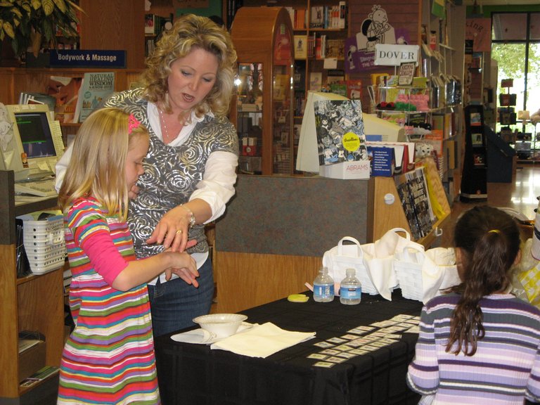 Here, Carmen Oliver and daughter work the press-on alien-head tattoo table.