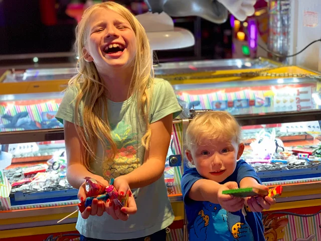 Children showing off the sweets they have won in the arcade with 10p slots in the background