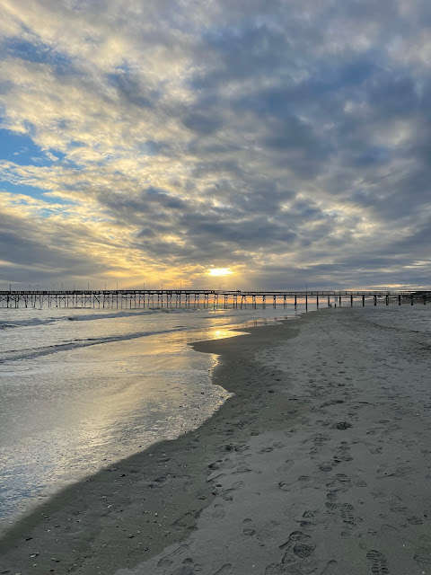 Late afternoon on the first day. The tide is moving out (I think) and the sky is beginning to cloud up partially covering up the sun. The pier is in the distance and there does not seem to be a single soul in view.