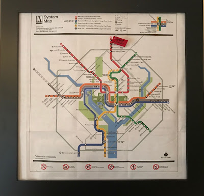 Metro system map in a frame with a red flag stuck into Forest Glen with a date and mileage on it