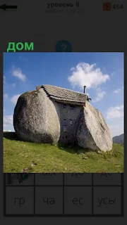 На зеленом холме стоит дом, который сделан из двух больших камней