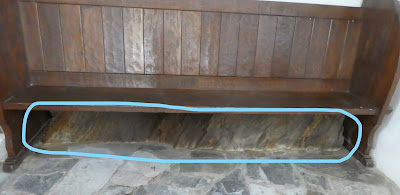 Wooden pew with bare rock visible underneath