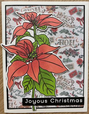 A Christmas card with a stamped poinsettia on a glitter coated patterned paper. The sentiment reads "Joyous Christmas".