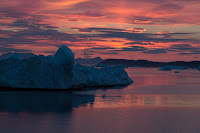 The setting sun paints a dramatic sky over icebergs in a fjord off west Greenland. UC Irvine glaciologists aboard the MV Cape Race in August 2014 mapped for the first time remote Greenland fjords and ice melt that is raising sea levels around the globe. (Credit: Maria Stenzel/for UC Irvine) Click to Enlarge.