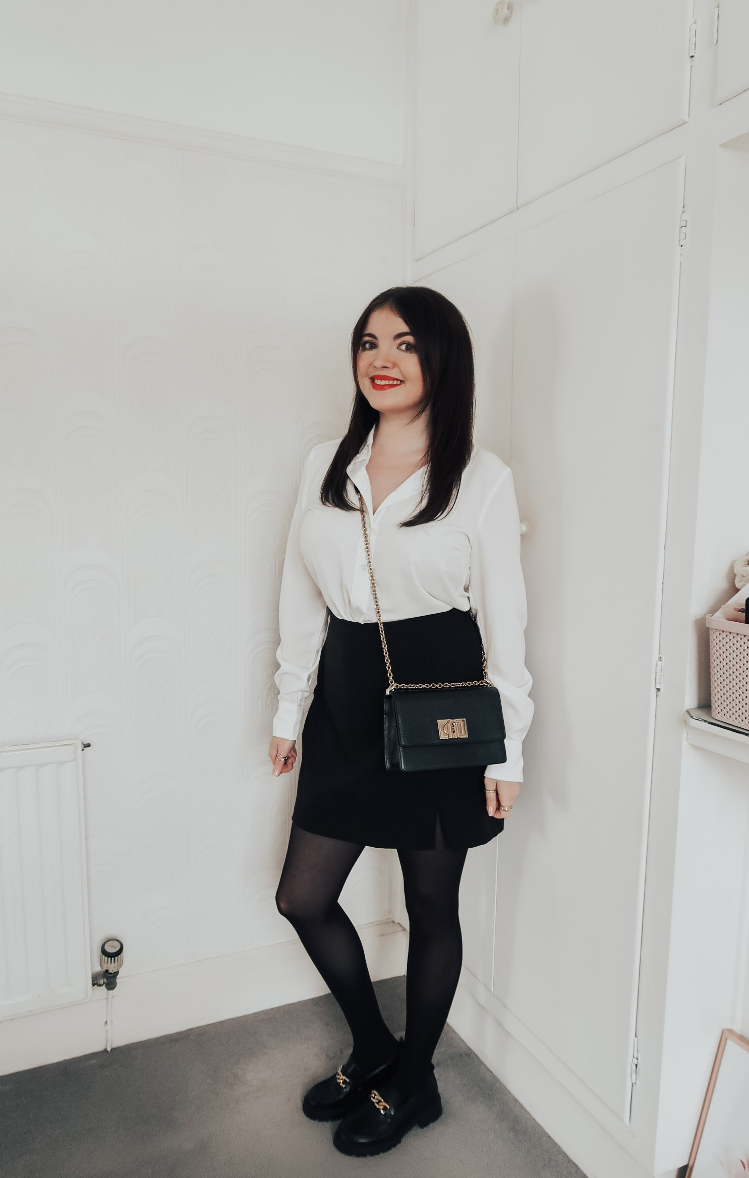 A woman wearing an ivory blouse and black mini skirt.