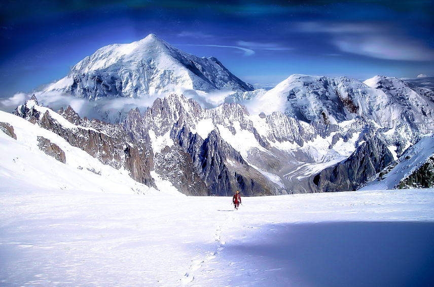 Un hombre atravesando montañas nevadas.