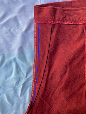 a close up of the seam in the centre back of a pair of dark red culottes. The fabric has been overlocked along the edge and there is a line of straight stitching 1.5 cm from the edge. There is another line of stitching that starts 7.5cm in from the edge underneath the waistband. It travels down 25 cm, tapering into the first stitching line at the bottom. End ID.