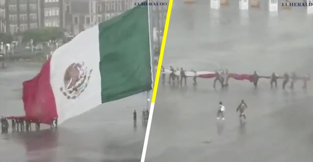 CAPTAN EL MOMENTO EN EL QUE VARIAS PERSONAS AYUDAN A MILITARES A BAJAR LA BANDERA DURANTE UNA FUERTE LLUVIA EN CDMX