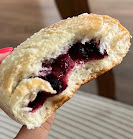 A bulberry filled bun, called a jagodzianka, either torn or bitten to show its filling and the spongy nature of the crumble toppedbun.