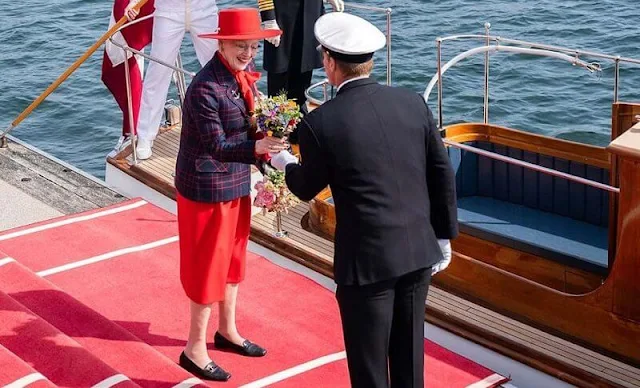 Queen Margrethe officially boarded the royal yacht Dannebrog. The Queen wore a red dress, and navy printed blazer, and red hat