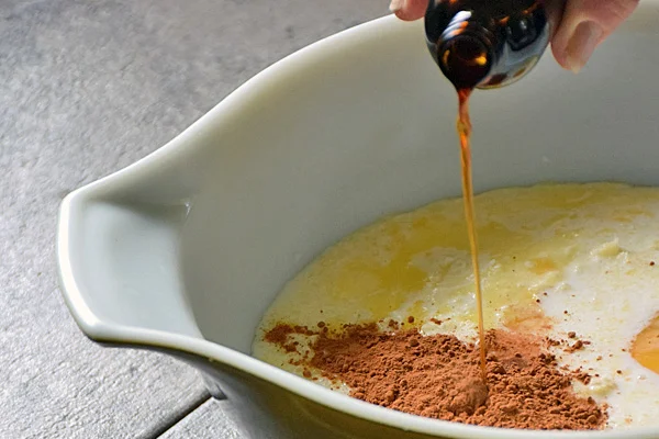 Adding pure vanilla extract to custard mixture in mixing bowl