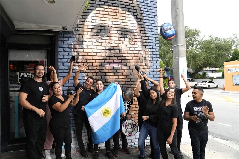 Staff at the Fiorito restaurant pose in front of a mural of Lionel Messi to celebrate