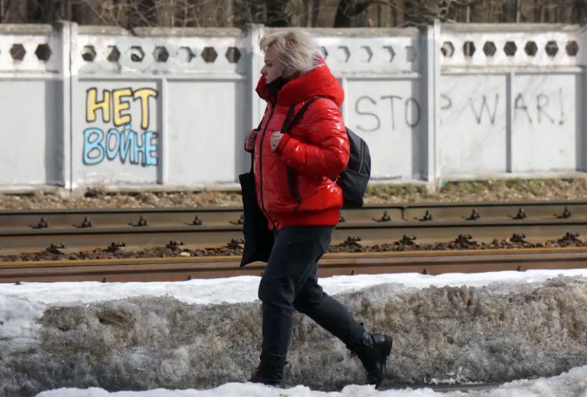 A woman walks past graffiti on a fence that reads "No war" and "Stops war" in Moscow, Russia, On March 14, 2022.