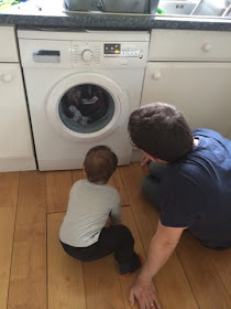 Baby boy and Daddy watching the washing machine 