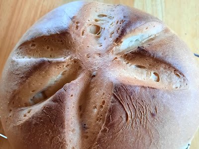 Closeup of round loaf of bread with crisscross on top.