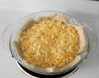 shredded cheese on flattened bread in pie plate