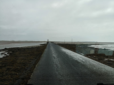 Photo of the causeway to Holy Island with the tide well out but traces of water and sand on the road.