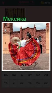 на площади в Мексике танцуют мужчина с женщиной в красном платье