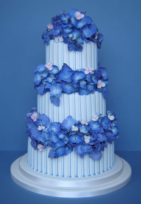 Stripy three tier white wedding cake with blue hydrangeas