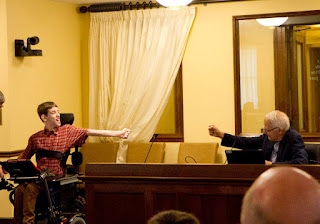 Justin in wheelchair reaching out with fist bump to Senator Durenberger