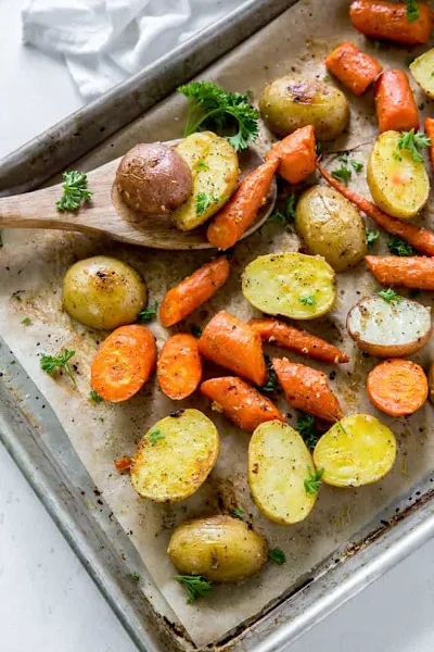 Top view of oven roasted potatoes and carrots on a baking sheet with parchment paper.