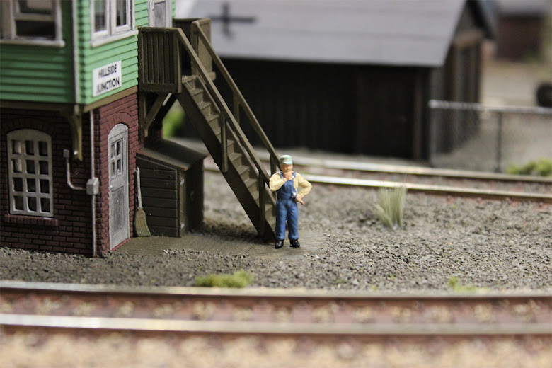 Model train mechanic figure standing in front of the stairs of an Atlas signal tower
