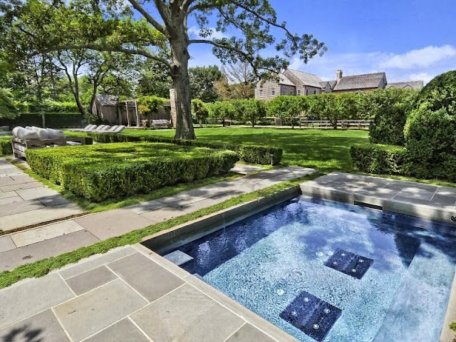 Backyard of an East Hampton compound with a pool, walkway and well kept hedges