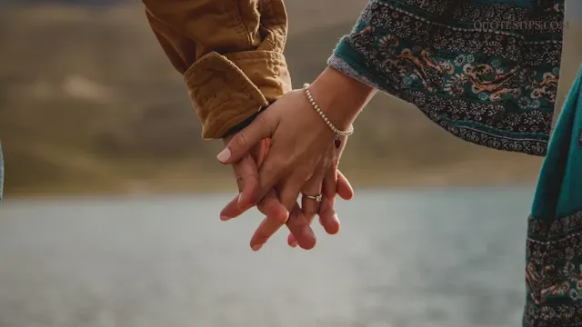 couple holding hands under a glowing sunset, symbolizing the depth and beauty of being in love.