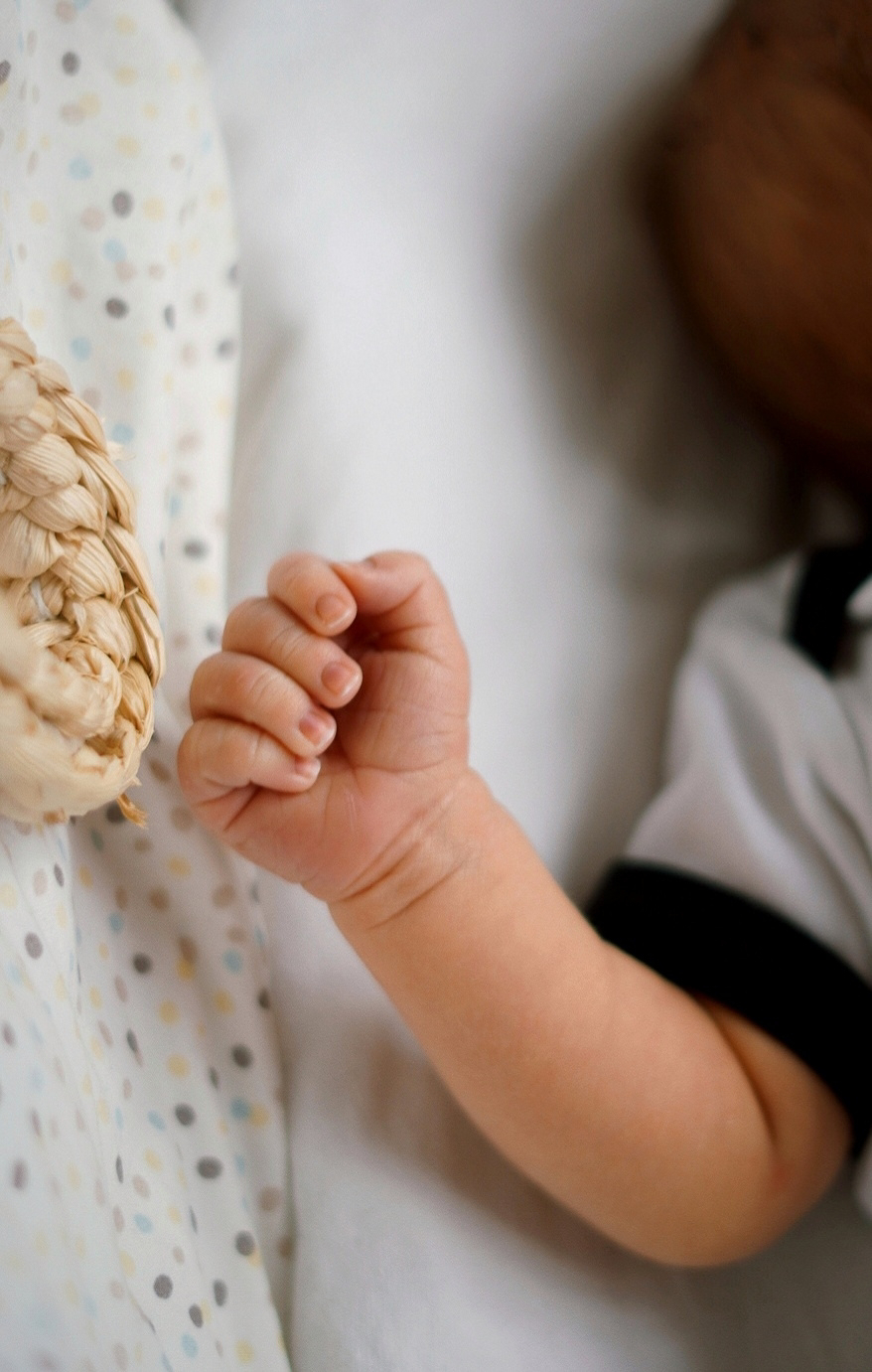 a small baby's hand and arm in a moses basket