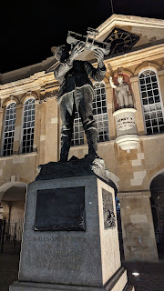 Statue of Charles Rolls at night with the Shire Hall and Henry V statue in the vackground, Monmouth