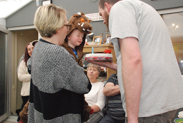 A little boy dressed as the Gruffalo blowing out candles