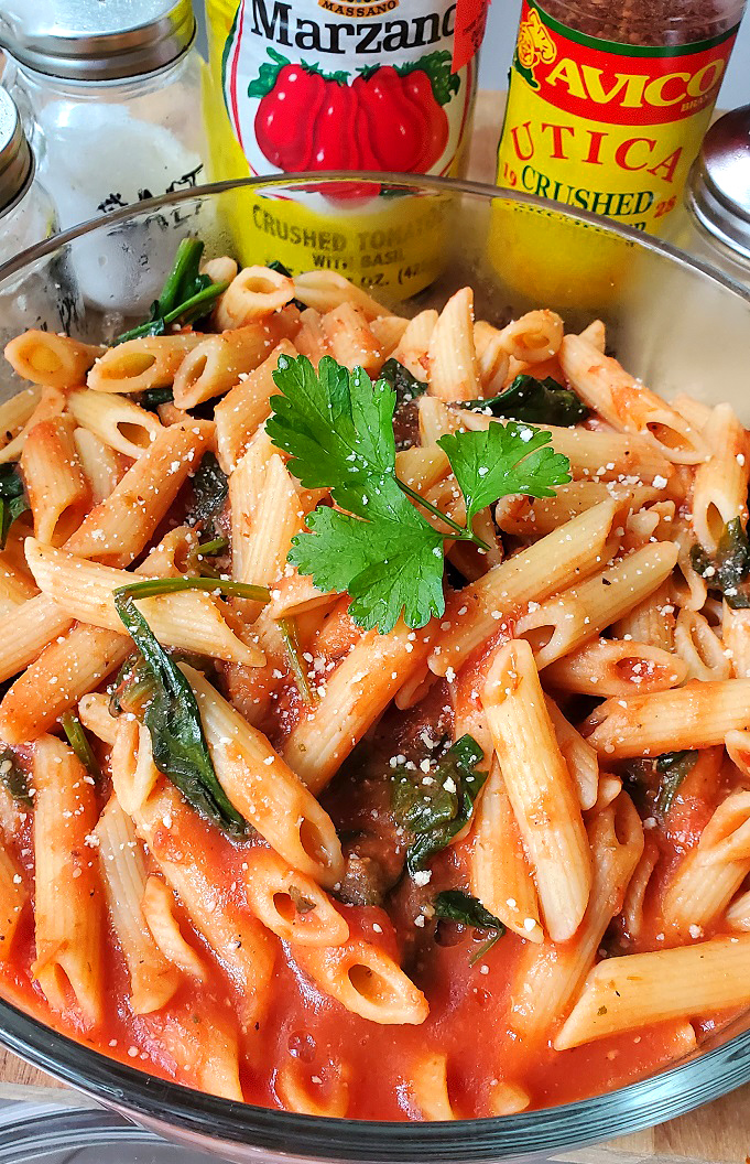 spinach in tomato sauce with penne pasta in a large bowl