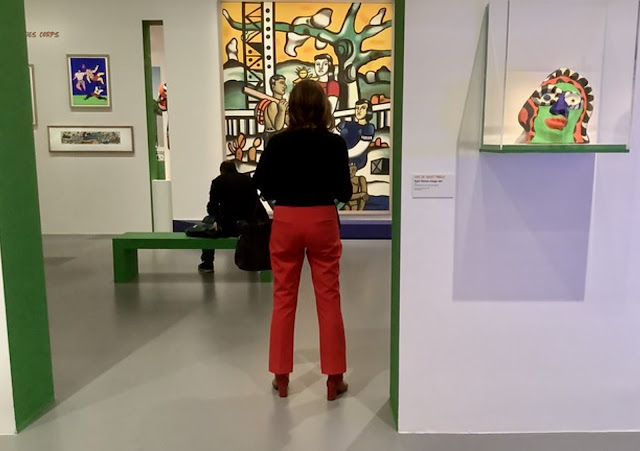 Woman in red pants next to green museum wall
