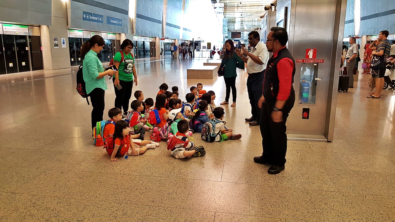 toddlers on a field trip, seated on the floor while listening to an explanation at Changi Airport MRT Station