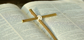image small cross made of two twigs and string in the centre of a large open Bible from Pixabay