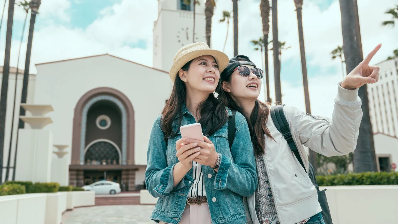 Two happy asian woman tourists searching location together with smart phone internet map app.