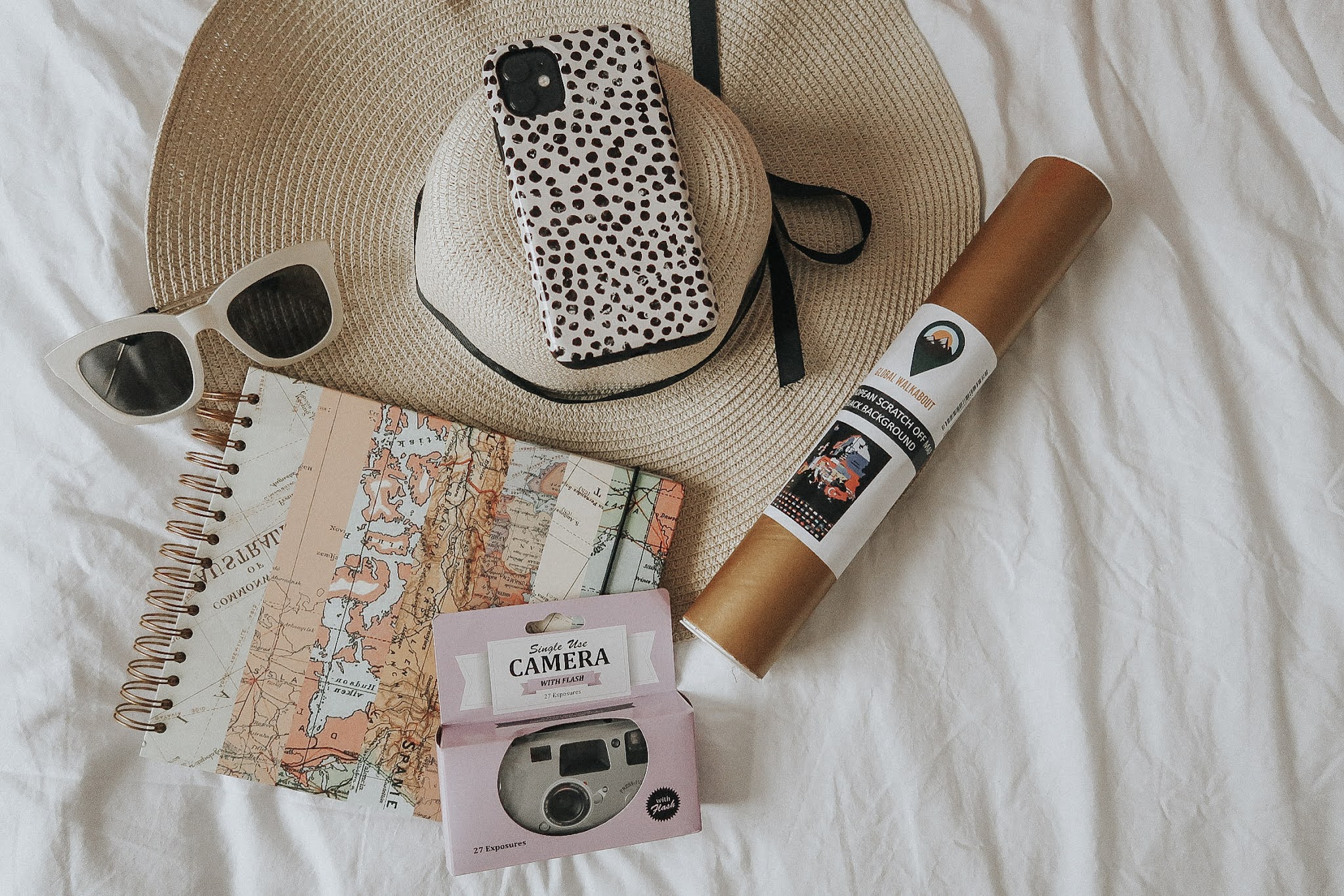 A purple disposable camera, white sunglasses, a gold rolled up map and scrapobook.