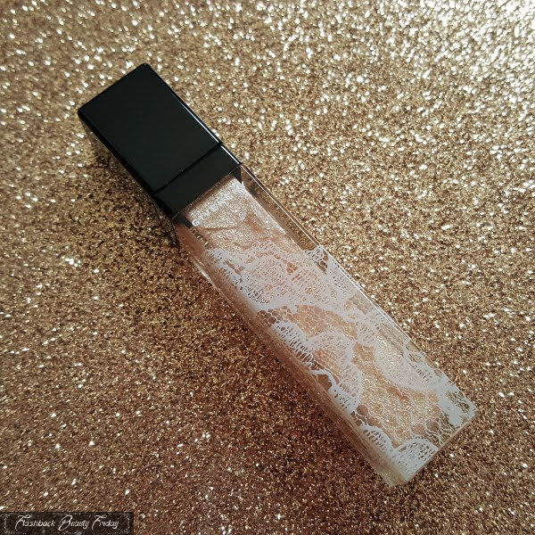 gold glitter lipgloss in lace design tube on gold sparkling background