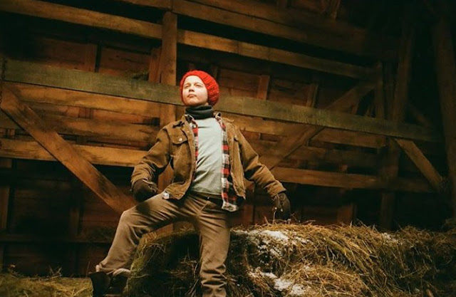 El actor sordo Danny Murphy en un pajar con gorro rojo, cazadora y pantalón marrones