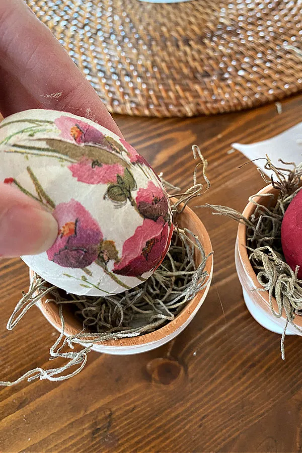 Placing a decoupage egg into a clay pot to form a nest