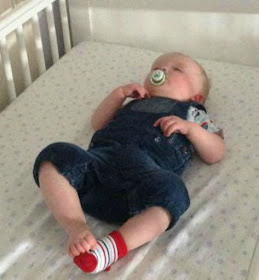 Baby lying on back asleep in cot