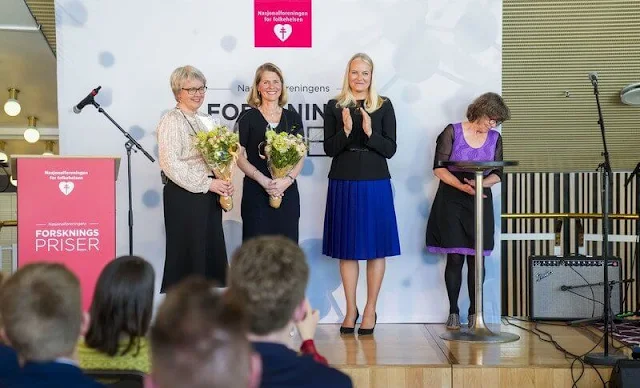 Crown Princess Mette-Marit wore a black jacket and a blue pleated skirt. Kristina Hermann Haugaa and Professor Ingvild Tina Saltvedt