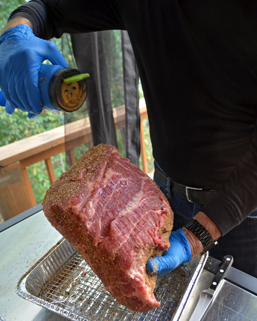 Seasoning a pork butt with green chile rub