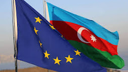 The photo shows two flags fluttering in the wind. On the left is the flag of Azerbaijan, and on the right is the flag of the European Union.
