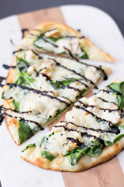 The finished Chicken and Spinach Naan Bread Pizza, cut into pieces, and drizzled with balsamic glaze.