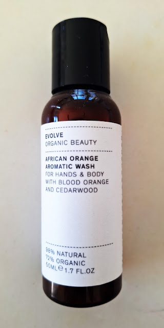 Evolve African Orange Aromatic Wash, Travel Size, orange brown bottle, black cap, white wraparound label, faded black font.