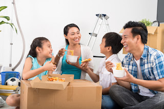 Vietnamese family sitting on the floor and eating noodles and pizza