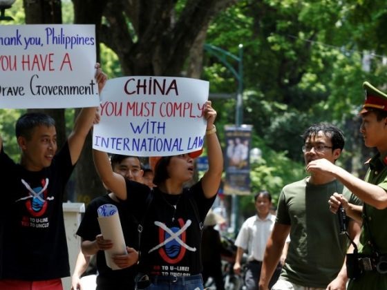 A policeman tries to stop anti-China protesters holding placards during a demonstration in front of the Philippines embassy in Hanoi, Vietnam. 