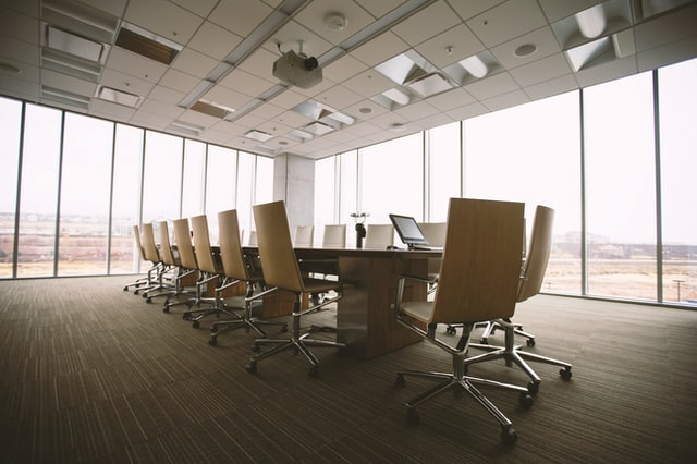 Long wooden desk and chairs in the middle of an empty room